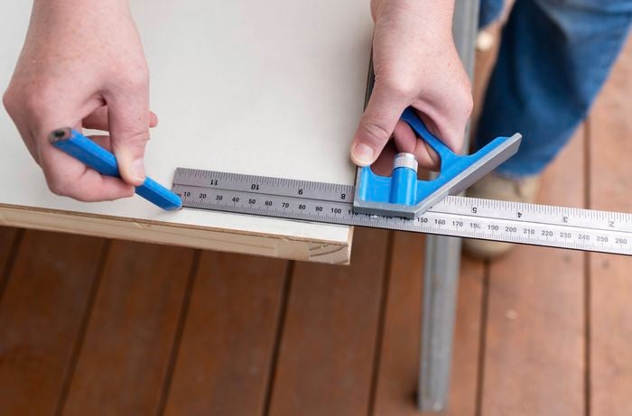 A person is carefully marking trim lines on the door to remove excess material and ensure an accurate fit within the frame.