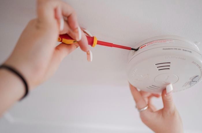person removing smoke alarm