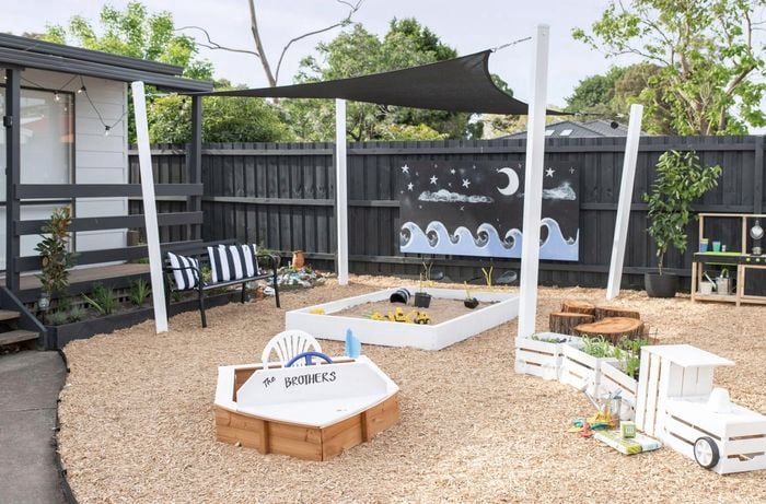 An installed black shade sail over a kindergarten sandpit