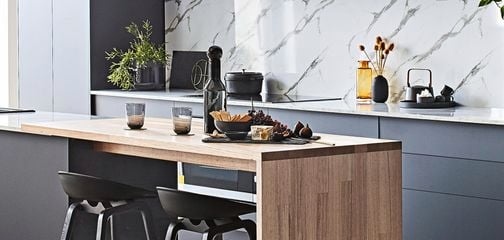 Modern kitchen with navy cabinetry, marble splashback and timber bench.