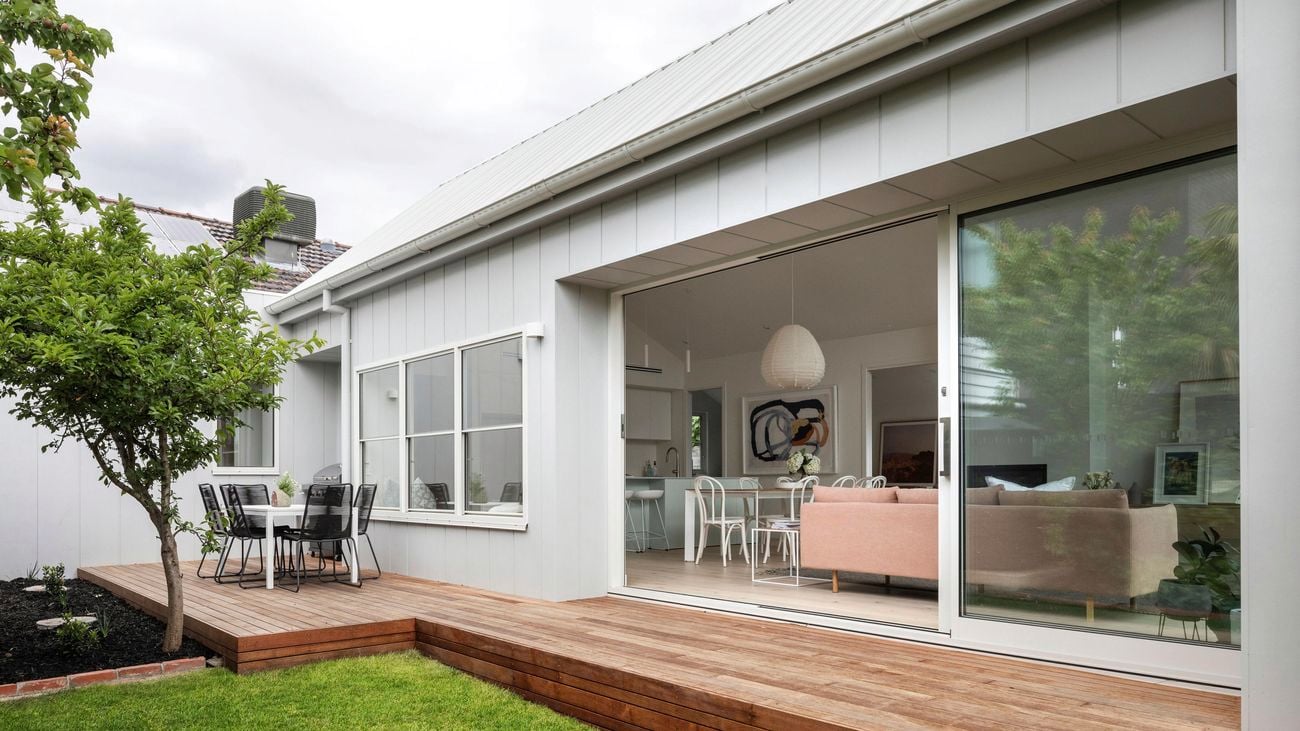Exterior of house extension with cladding and decking with outdoor setting.