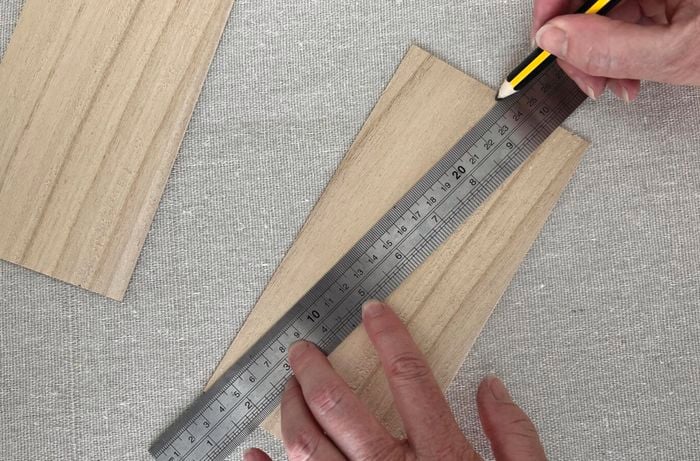 Hands use silver ruler to measure length of paper