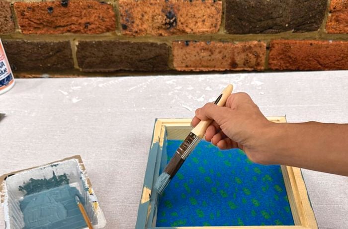 Painting a wooden picture frame with a dusty blue paint