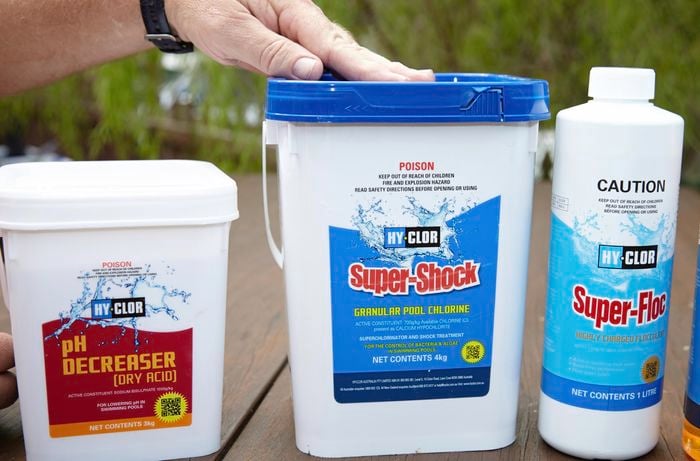 Containers of dry acid, granular pool chlorine and flocculent, substances used to treat pool water