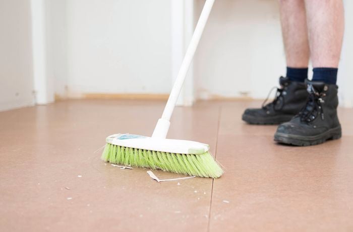 Sweep debris from the floor using a broom