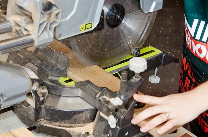 A person cutting a length of timber using a drop saw