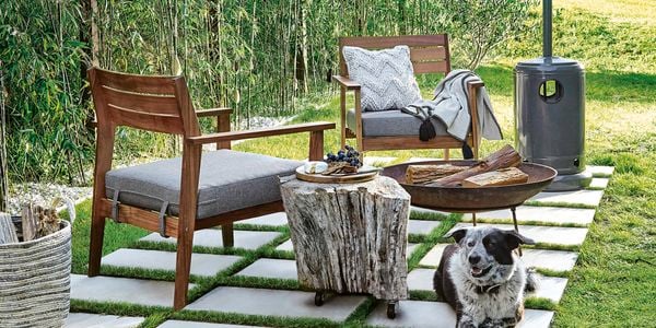 Outdoor armchairs on pavers next to a firepit and gas heater