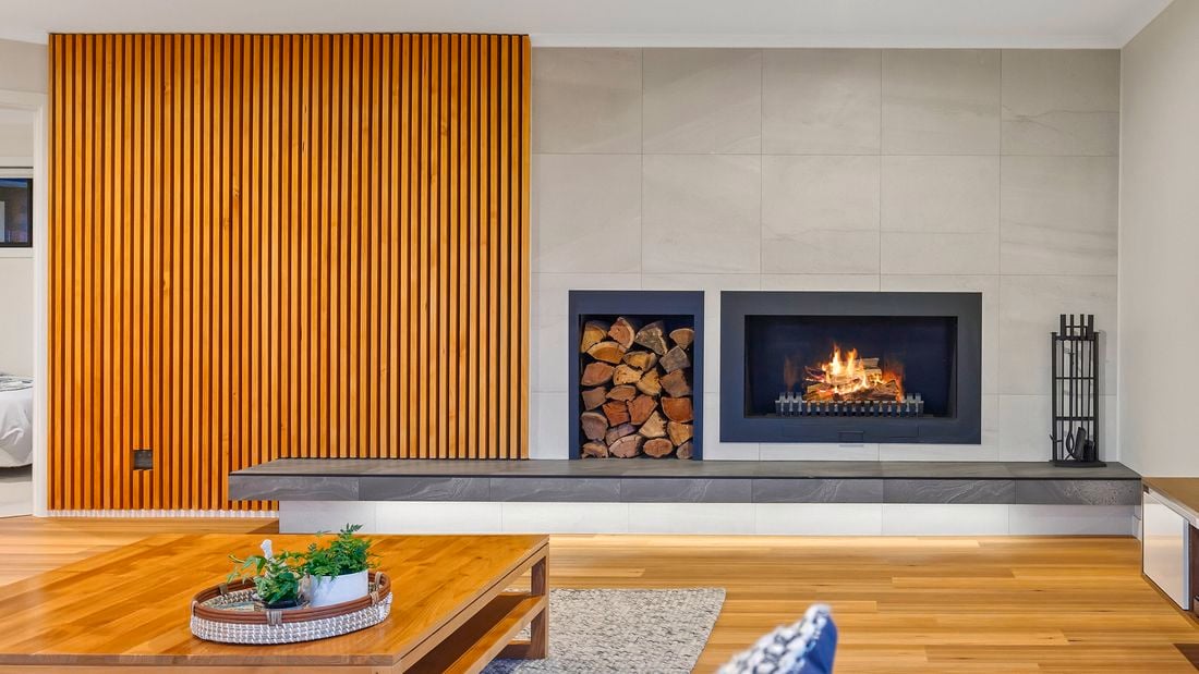 Modern living room with built-in fireplace, wooden slat wall, hardwood floors, and coffee