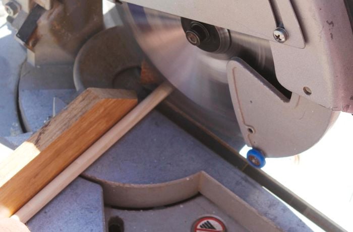 A mitre saw being used to cut a piece of dowel