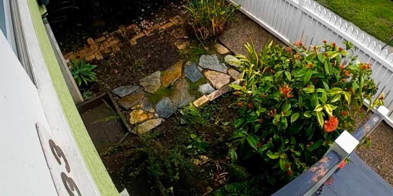 Pavers, plants in a front yard with a white fence.