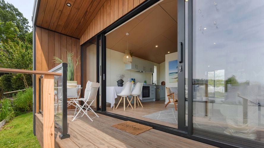 Timber deck with outdoor seating opening into light-filled open-plan living and kitchen area.