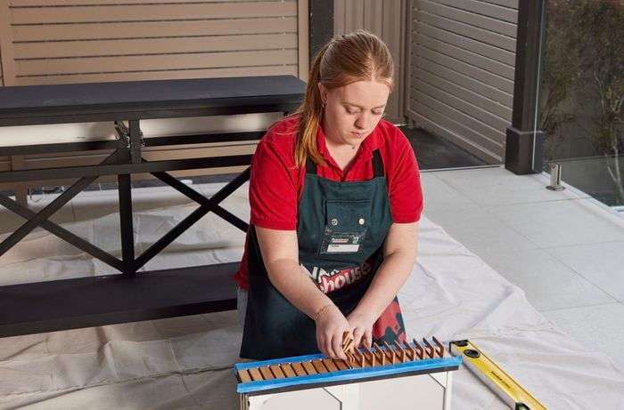 Person kneeling down, inserting spacers onto panel.