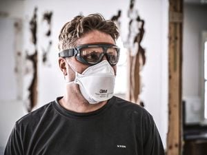 A tradesman wearing safety goggles and a protective mask