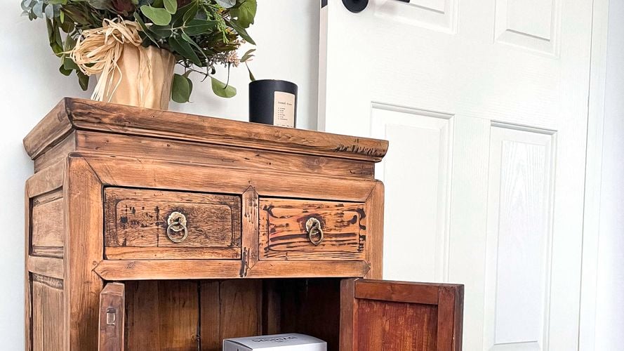 Rustic side table with plant and candle on top and books inside.