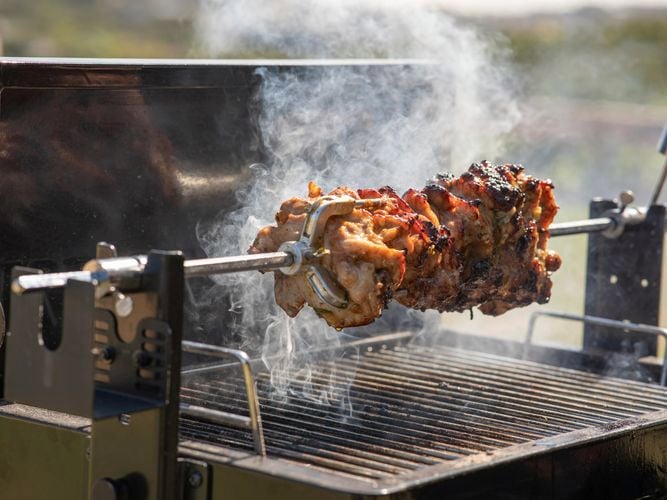 Large piece of meat skewererd on a spit roast cooking.