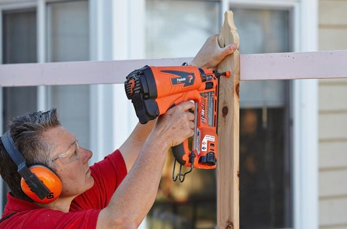 Fence palings being secured to a wooden rail using a nail gun