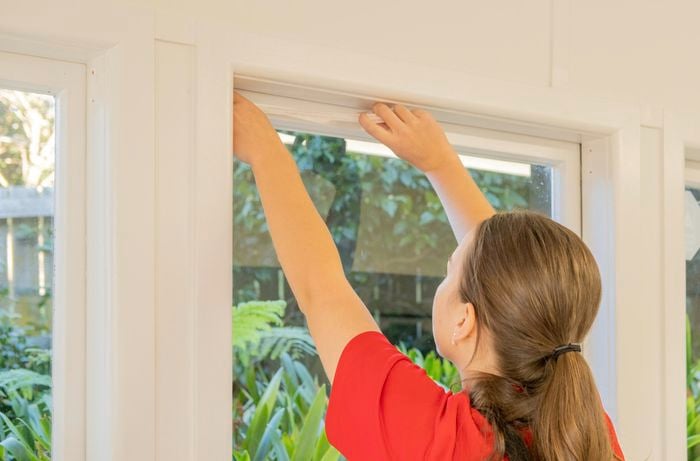 A Bunnings Team Member putting tape on a window