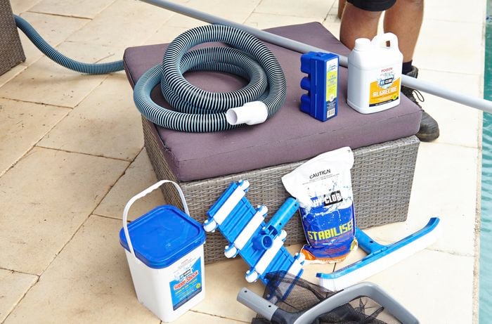 The tools and materials for maintaining a pool, including pool vacuum and hose, algaecide, pool broom, stabiliser, shock chlorine, a pool scoop, testing kit and broom handle