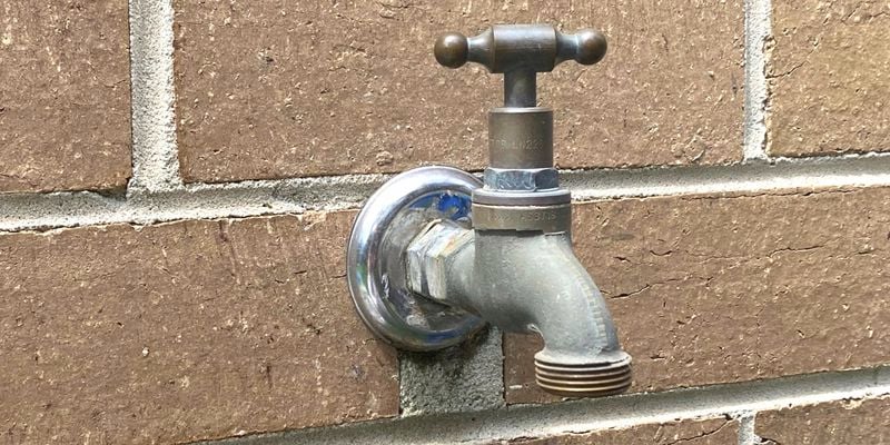 brass garden tap fixed to a brown brick wall
