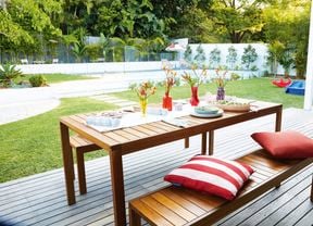 Outdoor decorated setting on a deck with a pool in backyard.