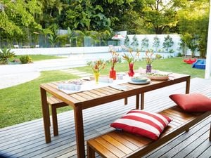 Outdoor decorated setting on a deck with a pool in backyard.