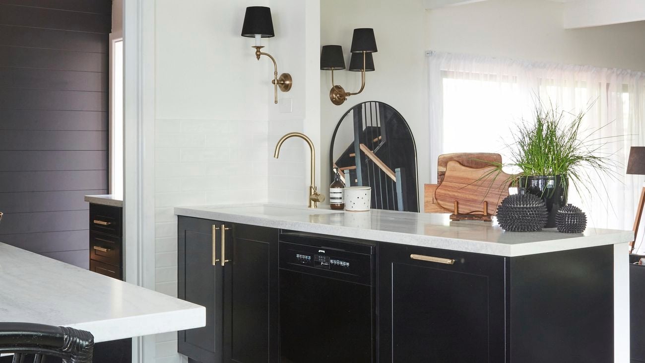 Modern monochrome ktichen with black cabinetry, gold coloured sink tap and handles