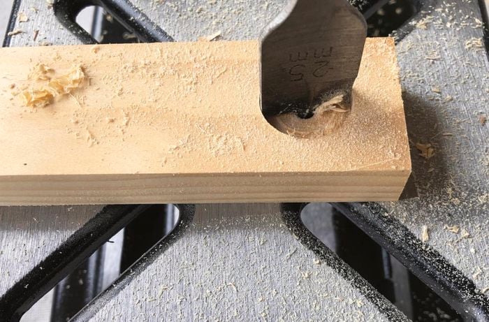 A hole being drilled in a piece of pine timber using a spade bit