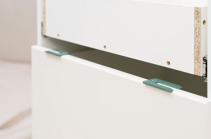 Use a spacer before fixing the next drawer front 