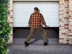 Man lifting up white garage door with bare hands