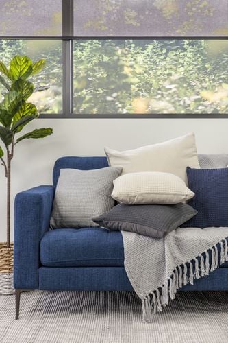 Living room with blue sofa and semi transparent roller blind on the window