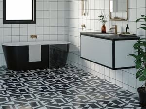 Bathroom with black bathtub and wash basin along with golden fittings, mirror and black and white floor.