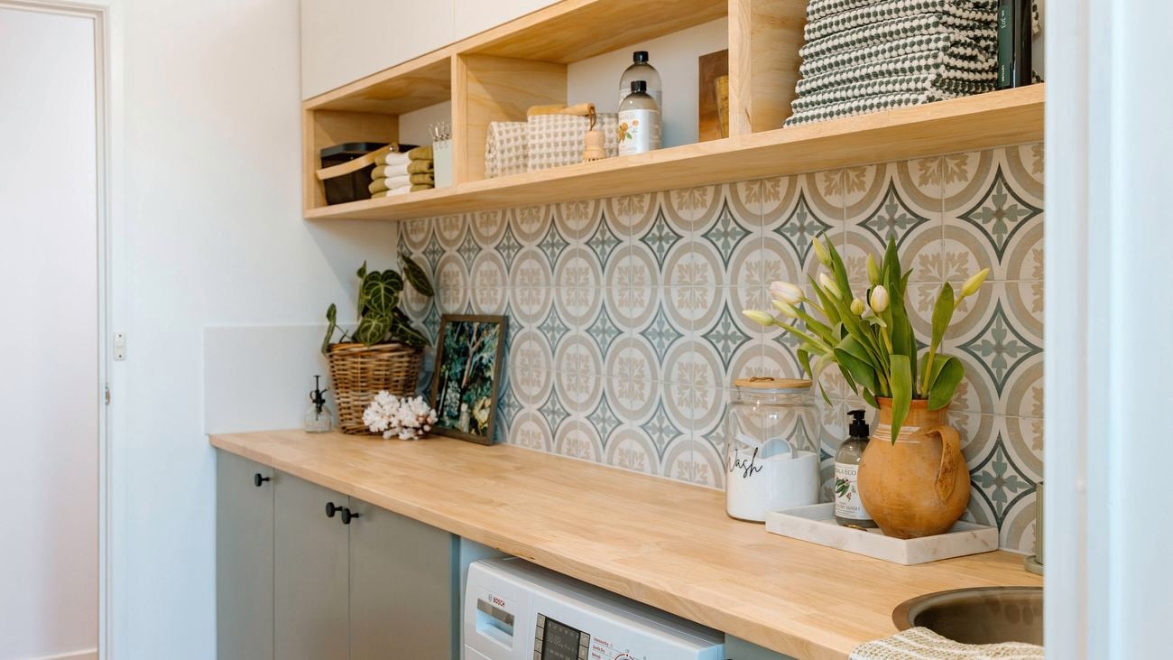 Updated laundry with timber bench tops, timber shelvomg and mosica green and blue wall tiles