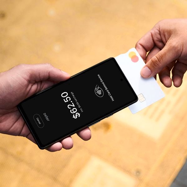 A person holding a card to a smart phone to make payment