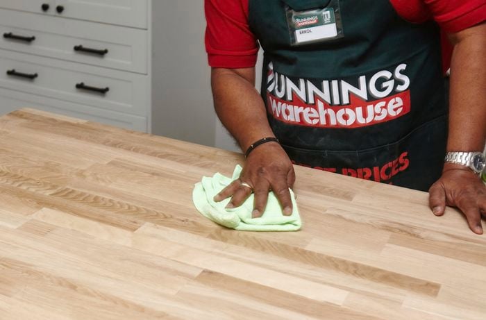 Person wiping benchtop with cloth.
