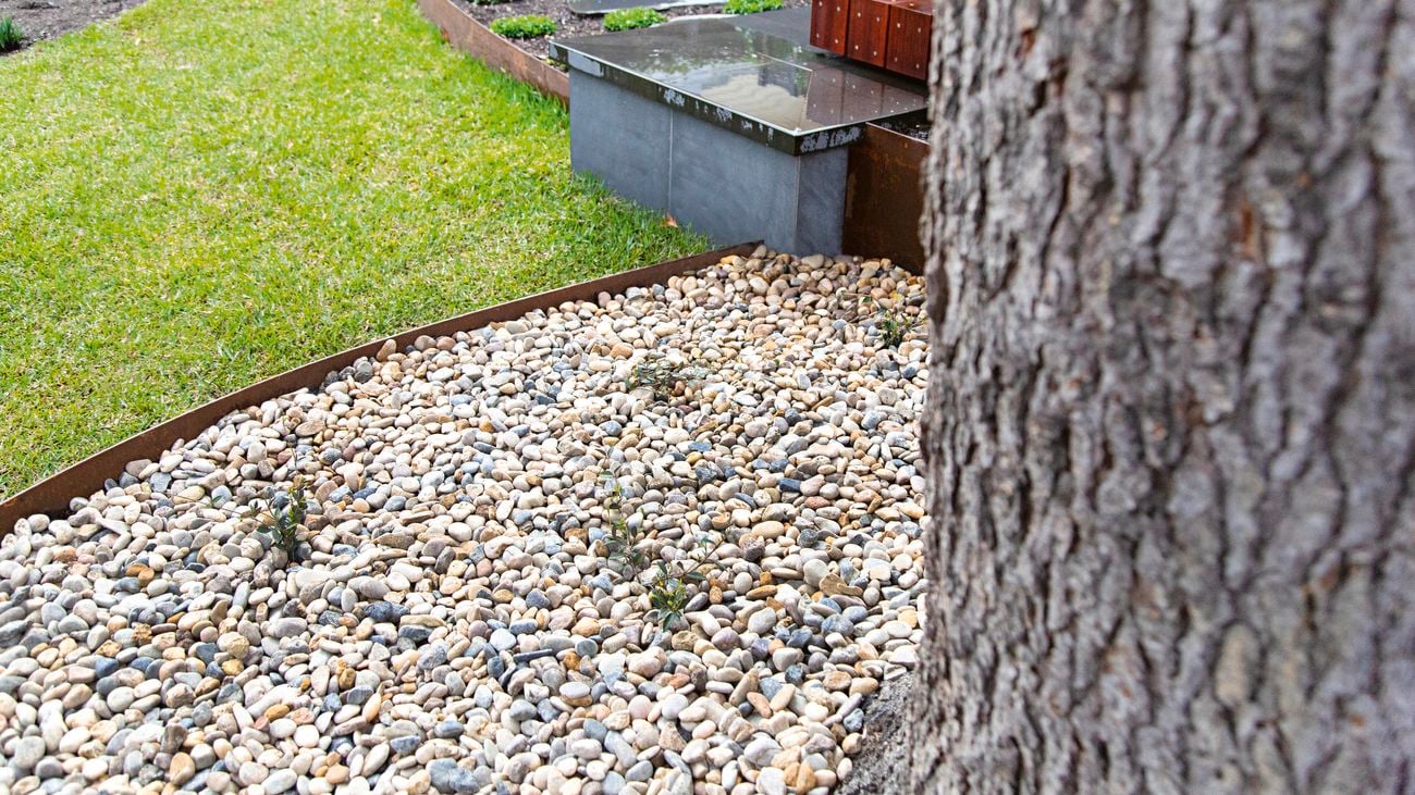 Curved garden landscaping featuring pebbles, pavers and garden edging