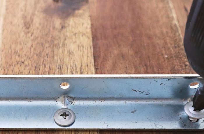 Metal brackets being screwed into a timber frame