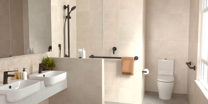 Modern beige bathroom with a toilet, 2 basin's, shower and a hand rail attached to the wall.