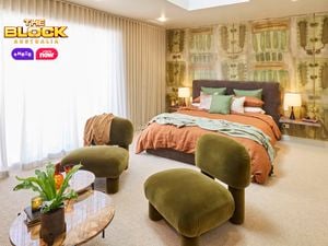  Bedroom with patterned green wallpaper, earthy bedding, and green velvet chairs.
