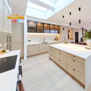 Modern open-plan kitchen and dining area featuring a large island bench, light timber cabinetry, pendant lighting and skylights.