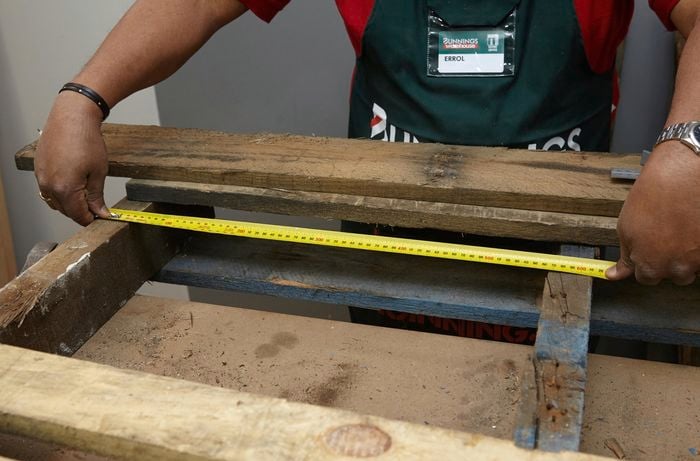 A person measuring the width of a pallet frame