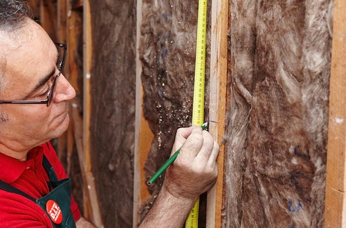 A pencil and tape measure being used to mark a villaboard join on a wall beam