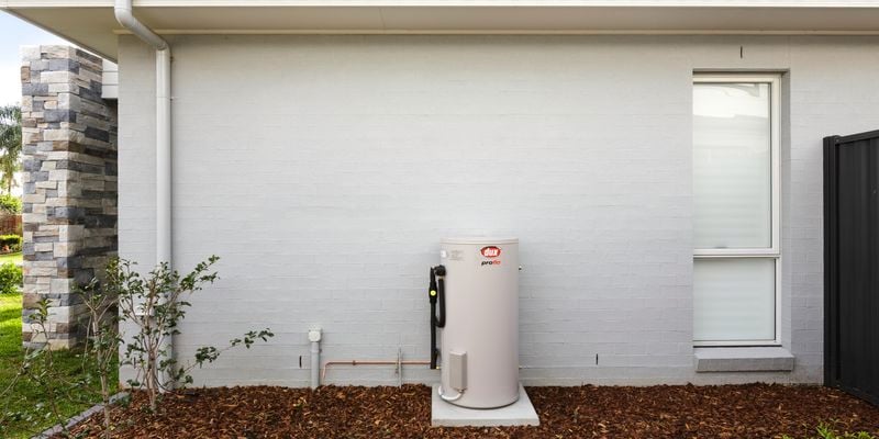 Hot water system located at the back of a rendered brick house