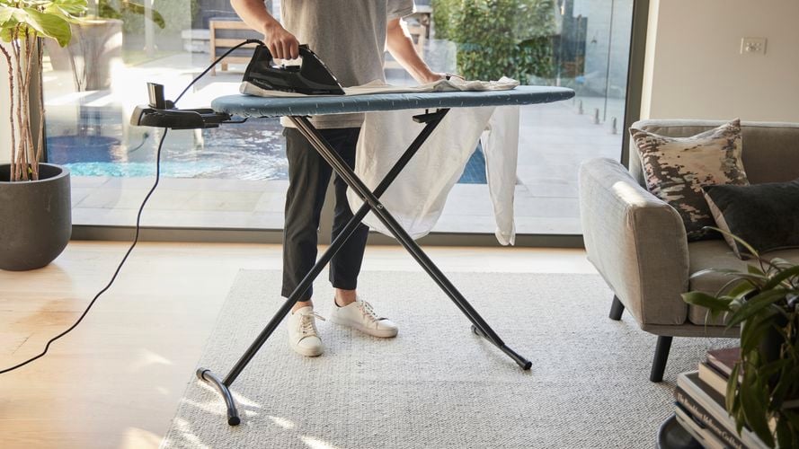 Man ironing a shirt using the Hills Large Ironing Board with Caddy.