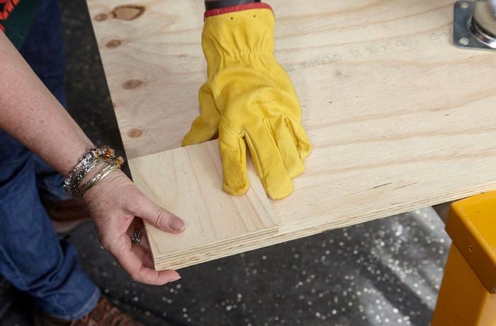 Raised corner of timber being positioned on a panel of timber for castor wheels