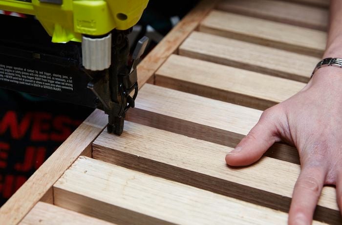 Person using nail gun to nail timber slats to frame