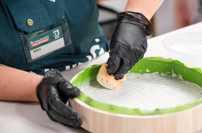 A Bunnings Team Member holding a sponge against the top of a side table