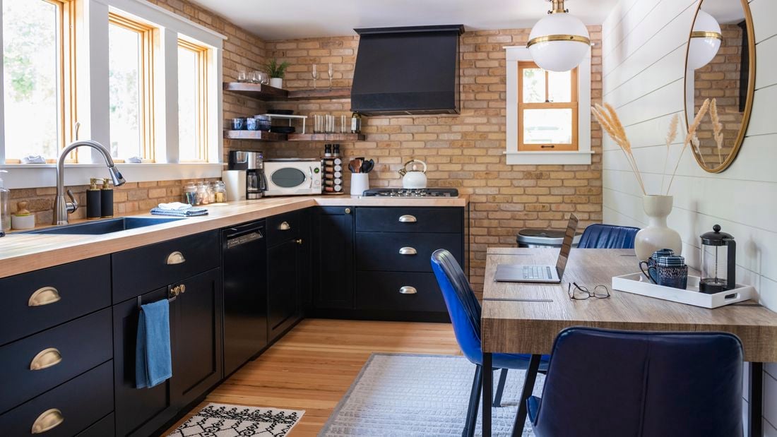 A vibrant white and blue themed kitchen with bare bricks and wooden panelling