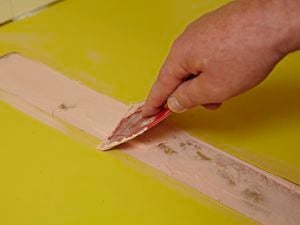 Putty being used to fill gaps in a laminate benchtop