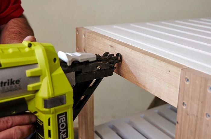 Person nailing timber to shelving unit
