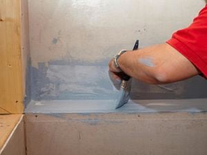 A person painting around the edge of a bath